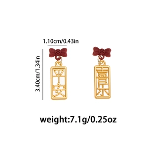 Detalle de los pendientes asimétricos rojos y dorados con símbolos de buena suerte