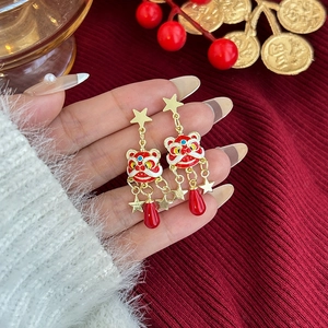 Detalle de pendientes de león chino rojo con esmalte y estrellas doradas fijas