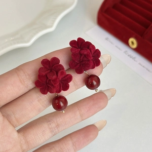 Detailed view of red velvet floral earring with glossy bead in a velvet jewelry box