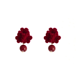 Detail showing red velvet rose earrings with tassels and pearl accents in macro view