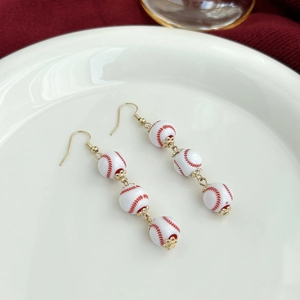 Detail of baseball theme drop earrings featuring white beads with red stitching patterns