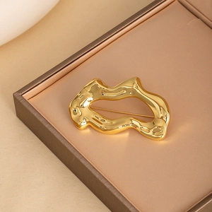 Broche géométrique irrégulière en métal doré brillant présentée dans un écrin à bijoux