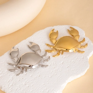 Elegant gold and silver crab-shaped brooch pins on a stone pedestal with a polished finish