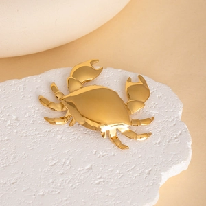 Luxurious gold metal crab brooch with polished mirror finish on white stone stand