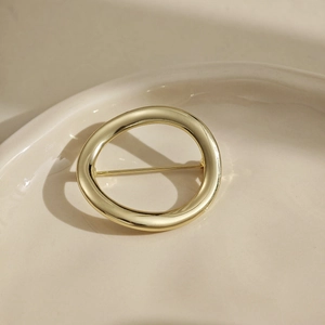 Broche ronde géométrique dorée minimaliste avec finition métallique polie sur plateau