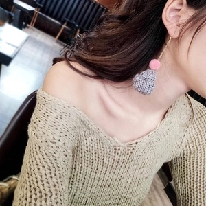 Detail of creative Christmas hat earrings with pink plush ball on a model wearing a sweater