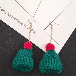 Detail of green knitted Christmas hat earrings with red pom-poms and gold chain