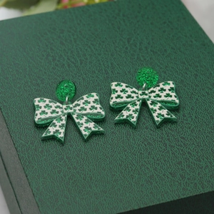 Macro shot of green St. Patrick's Day bow earrings with clover patterns on a leather box