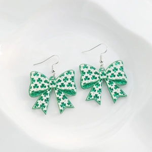 Detail view of acrylic bow earrings with green shamrock pattern and glitter for St. Patrick's Day