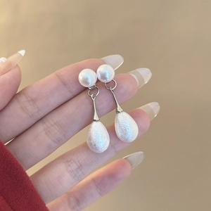 Dettaglio di orecchini a goccia d'argento opaco con eleganti perle finte pendenti