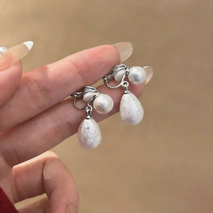 Dettaglio macro di orecchini a clip retrò francesi con perle a goccia testurizzate