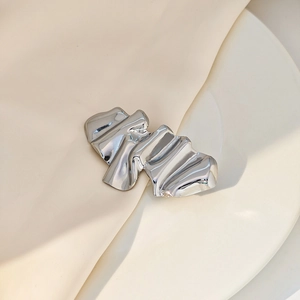 Detailed macro view of silver irregular pleated metal brooch with mirror polished finish
