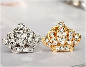 Dettaglio delle spille a corona in oro e argento con strass scintillanti per camicie