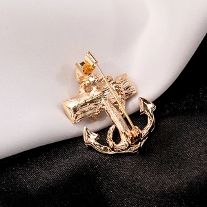 Fashionable gold anchor brooch with intricate rope detail on premium silk background