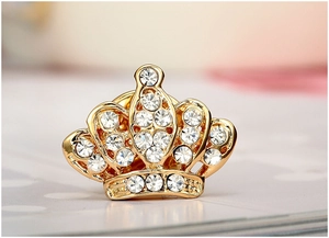 Macro di una spilla a corona dorata con strass scintillanti per abiti e camicie