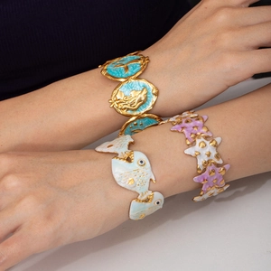 Dettaglio di bracciali a tema oceanico con ciondoli a sirena, pesce tropicale e stella marina