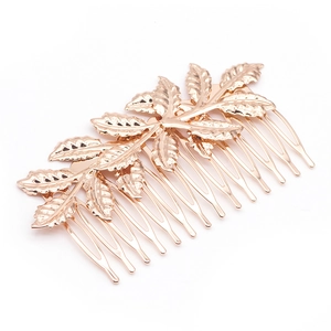 Close-up of golden leaf metal hair comb accessory with detailed texture on white background