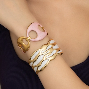 Dettaglio di bracciali smaltati rosa e bianco con finitura dorata sul polso di un modello