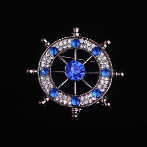 Vintage nautical helm brooch with sparkling blue and white rhinestones on black background