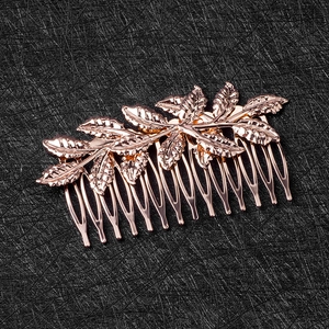 Close-up of rose gold leaf hair comb with detailed metal texture on black background
