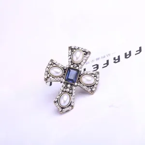 Detailed macro view of vintage cross brooch with pearls and blue crystal inlay