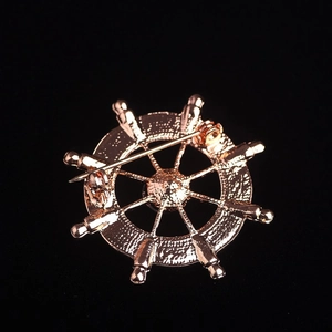 Detailed back view of rose gold nautical helm brooch with a secure locking pin fastener