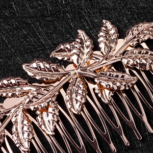 Close-up of rose gold leaf hair comb with detailed veins on black leather background