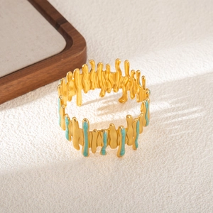 Dettaglio di un bracciale aperto placcato oro irregolare con smalto verde menta e linee fluide