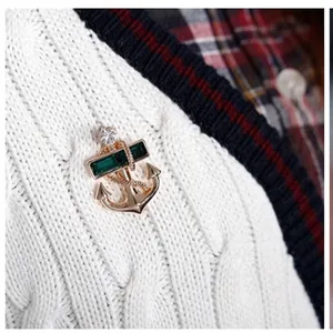 Unisex gold anchor brooch with emerald green gemstones and sparkling crystals on white knitwear