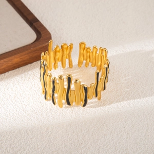 Dettaglio di un bracciale in acciaio dorato con motivo a goccia in smalto nero