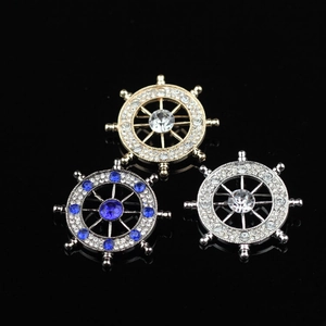 Sparkling vintage ship wheel brooches with rhinestones and blue crystals on black background