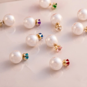 Macro detail of double-sided pearl earrings featuring multi-colored cubic zirconia in gold