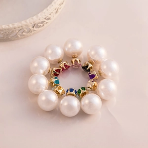 Detail view of double-sided earrings featuring colorful crystals and white pearls