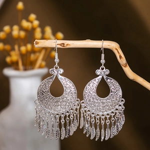 Nahaufnahme von Vintage Silber Pfau Feder Quaste Ohrringe an Holz Zweigen hängend