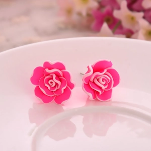 Detailed close-up of vibrant pink multi-layered rose stud earrings on a white ceramic plate