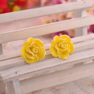 Vibrant yellow multi-layer rose stud earrings displayed on a miniature white garden bench