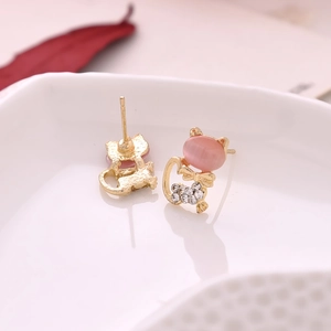 Detail shot of cute cat earrings with pink opal stones and white rhinestones on white ceramic