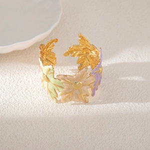 Dettaglio del bracciale rigido dorato con motivi floreali in smalto colorato e foglie