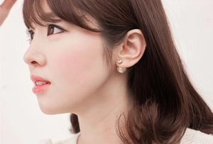 Elegant double-sided pearl earrings featuring a zircon stud on a model's ear