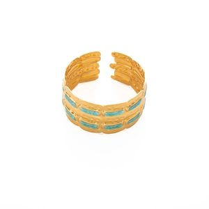 Dettaglio macro di un ampio bracciale a polsino dorato con inserti in smalto verde