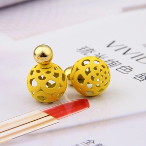 Detailed macro view of yellow hollow sphere drop earrings with dual-ball design