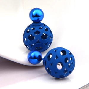 Macro detail of blue hollowed-out double-sided ball earrings with metallic finish