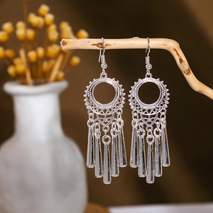 Nahaufnahme von silbernen Quastenohrringen an Naturholzzweigen im Boho-Stil