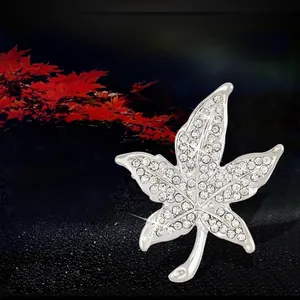 Gros plan d'une broche en feuille d'érable argentée ornée de strass en cristal brillant