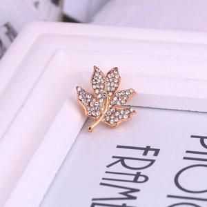 Gros plan sur les cristaux étincelants d'une broche feuille d'érable en métal doré rose