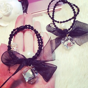 Detail of black organza bow hair tie with faceted acrylic bead and pearl pendant