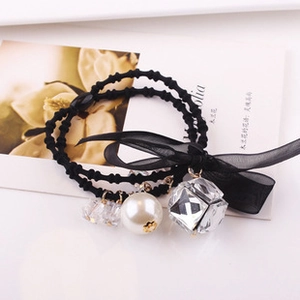 Detail of elegant black hair tie with faux pearl, crystal cube, and organza bow knot