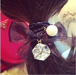 Detail of dark bow hair tie with large white pearl and faceted crystal cube charm