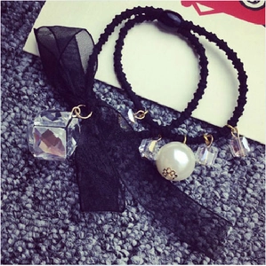 Detail of black organza bow scrunchie with white pearl and faceted cube charm