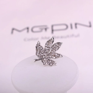 Broche en forme de feuille d'érable en métal argenté ornée de cristaux blancs